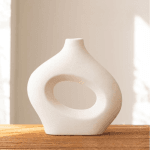 Imagine cu un living modern, dotat cu un colțar gri, lampă de podea minimalistă și decor rafinat, inclusiv plante verzi și opere de artă pe perete.